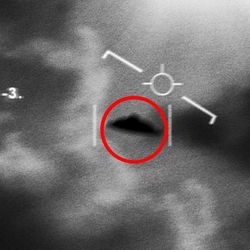 A blurred black and white photo that looks like a military camera tracking UFO in the sky. The saucer-shaped object is in the middle of the image surrounded by clouds. There is a red circle around it and markers on the frame to indicate its position.  