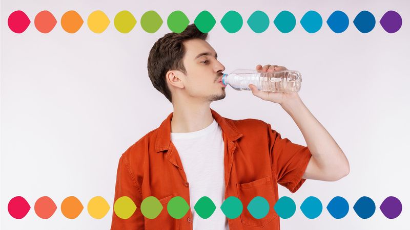 man wearing orange shirt and drinking from a bottle of water, along the top and bottom of the image is a rainbow of coloured droplets to represent a pH scale