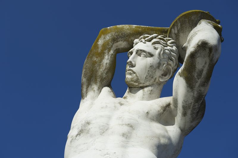 statue of a discus thrower, visible from the torso up against a clear blue sky