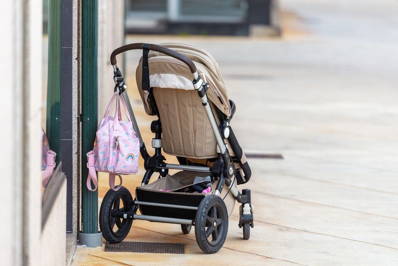 A brown pushchair left outside a building on a city street.