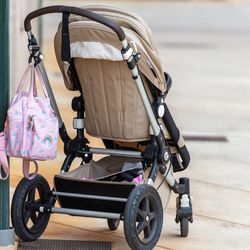 A brown pushchair left outside a building on a city street.