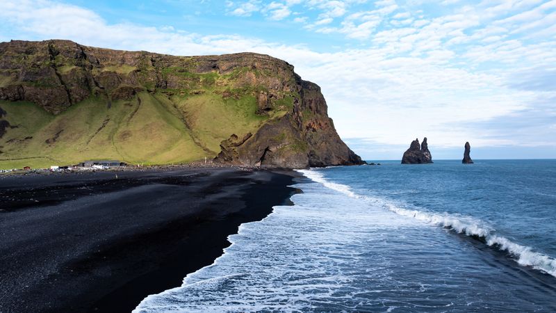 Aerial view of Reynisfjara black sand beach and sea stacks in Iceland.