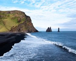 Aerial view of Reynisfjara black sand beach and sea stacks in Iceland.