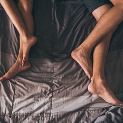 Close up of the legs of a couple on the bed.