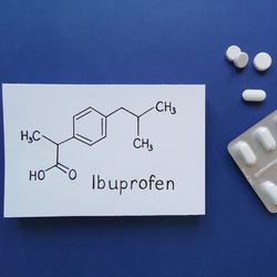 Blister packet of white pills next to a drawing of Ibuprofen's structure on a blue background