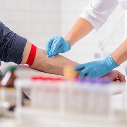 clinician disinfects man's arm before blood is taken, with medical equipment out of focus in the foreground