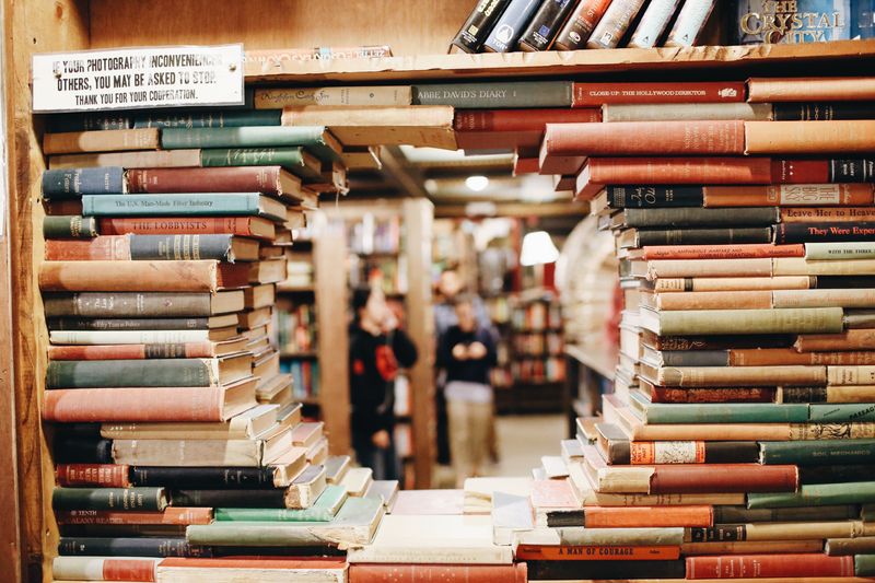 books in a library on brown wooden shelf with people talking.