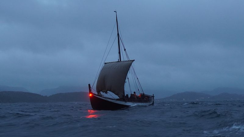 A photo of one of the recreated Norse expeditionary vessels sailing at night.