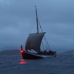 A photo of one of the recreated Norse expeditionary vessels sailing at night.