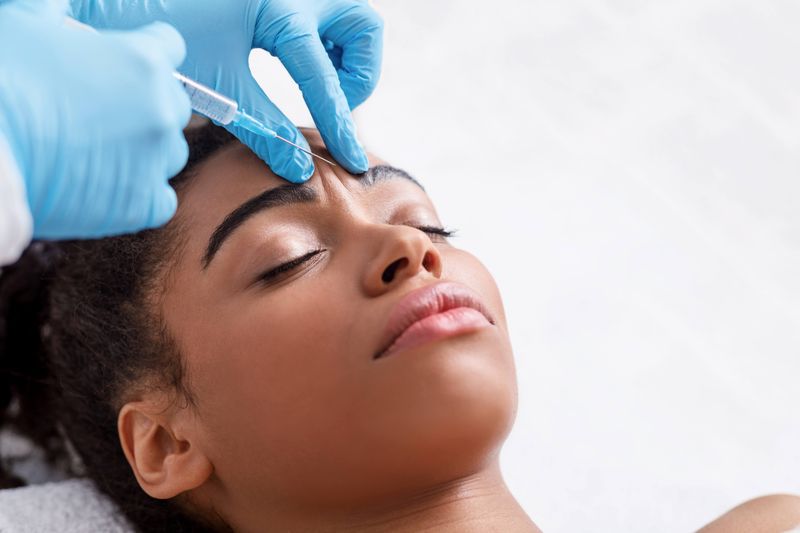 A woman receives an injection of Botox to her forehead. 