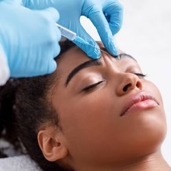 A woman receives an injection of Botox to her forehead. 