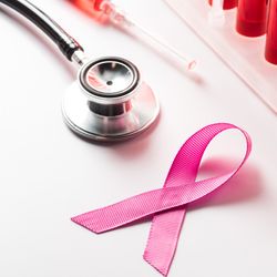 pink breast cancer awareness ribbon next to stethoscope and rack of tubes containing red liquid