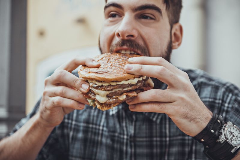 man wearing plaid shirt eating a burger