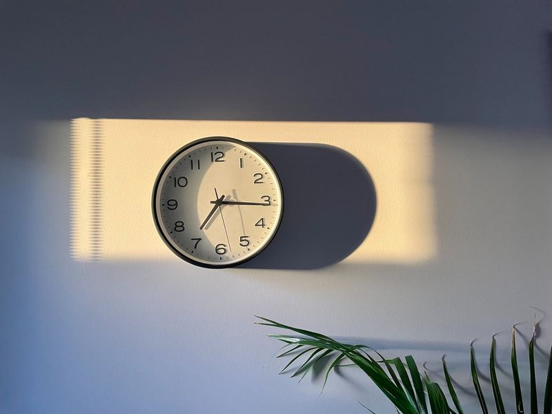 A clock on a wall with a shadow shows the passage of future time with