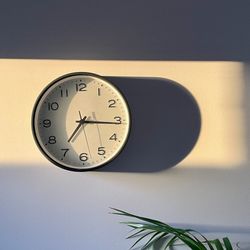 A clock on a wall with a shadow shows the passage of future time with