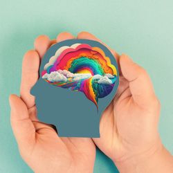 hands holding silhouette of human head with rainbow colored brain against light aqua background