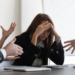 Five people having an argument, one with her head in her hands