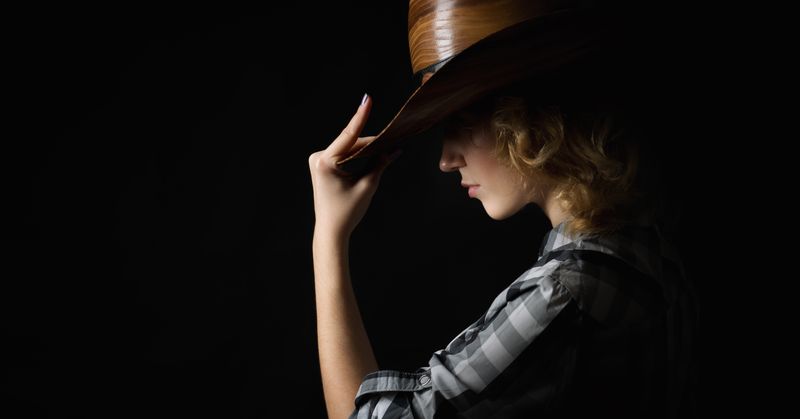 Woman in a cowboy's hat isolated on black background