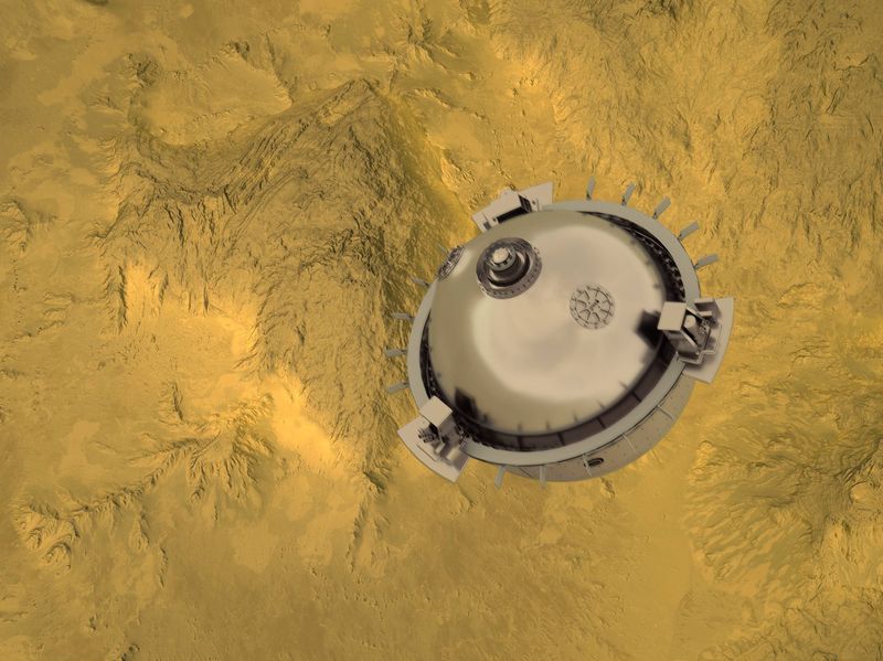 A spherical metal probe is seen floating above some yellow rugged mountains