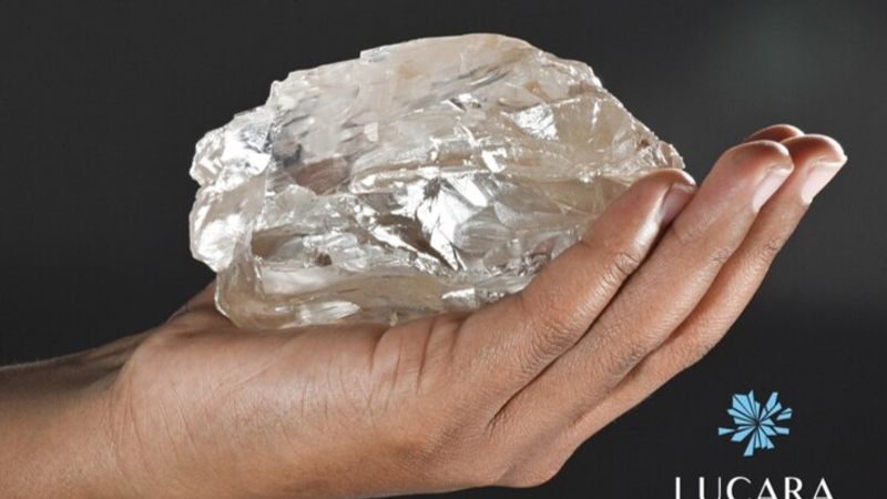 close up of a hand holding a giant rough diamond