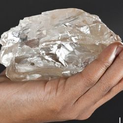 close up of a hand holding a giant rough diamond