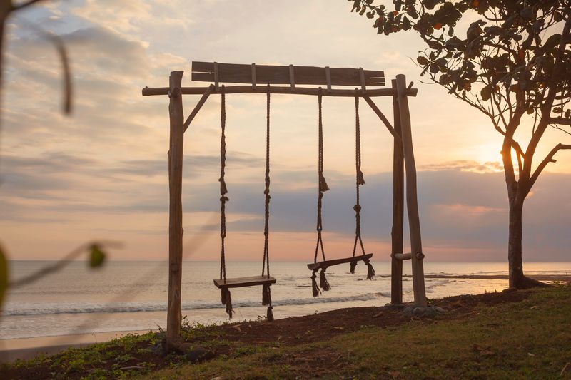 Empty swings in front of a sunset