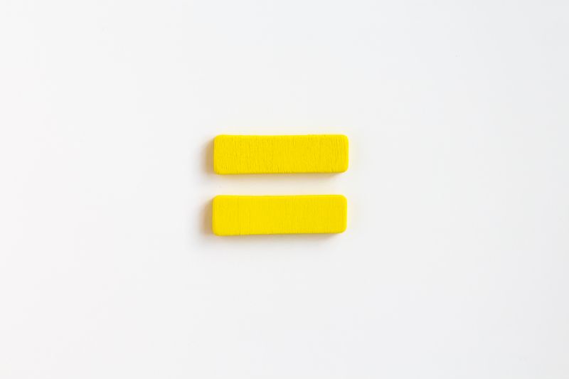 yellow painted wooden equals sign on white background