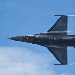 An F-16 fighter jet doing a flying maneuver in the sky. 