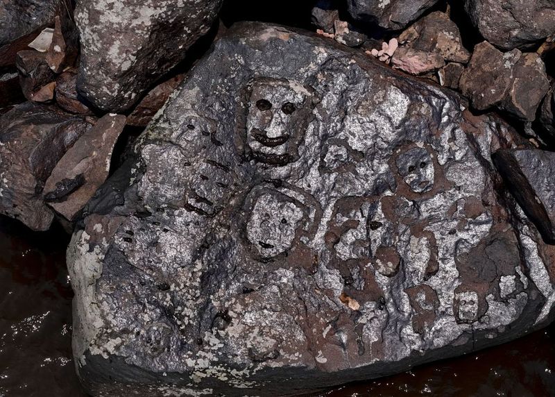 A series of faces engraved on a rock.