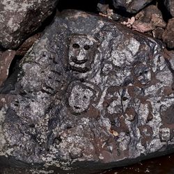 A series of faces engraved on a rock.