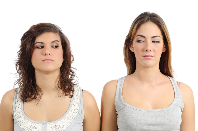 Two women standing side by side giving each other a side eye