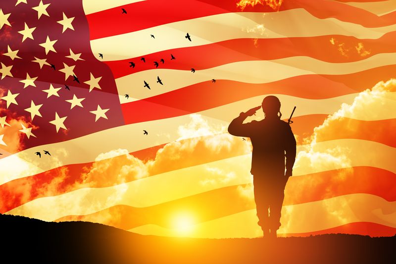 USA army soldier saluting on a background of sunset or sunrise and USA flag. 