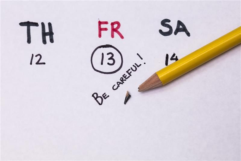 A photo of a hand drawn calendar showing Thursday 12, Friday 13 and Saturday 14. The days name's are represented as TH, FR, and SA, respectively, and the dates are below them. FR has been written in red and the number 13 has been circled in black. There is a yellow pencil resting across the image and its tip has broken.  