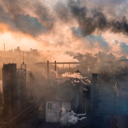 A picture of an industrial complex releasing smoke from many chimneys