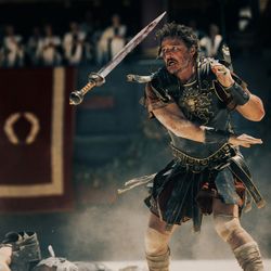 Paul Mescal and Pedro Pascal appear to be duelling in the Roman Colosseum, a still from the motion picture trailer. The two men are wearing leather armour and a sword is hanging in the air, presumably from someone having been disarmed.   