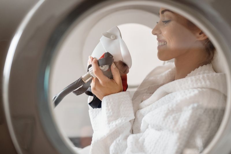 Side view of happy woman receiving oxygen therapy at hyperbaric chamber at health spa.