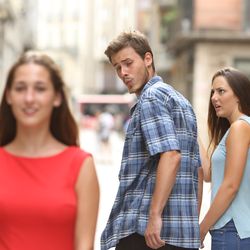 Disloyal man walking with his girlfriend and looking amazed at another girl