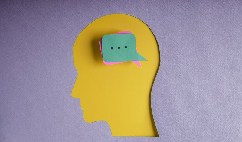 Paper cutout of the human head with message boxes as thoughts