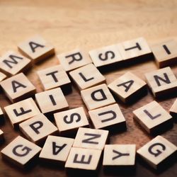 scattered wooden tiles with different letters of the alphabet on a wooden table, some of the letters are upside down and they're not in any order