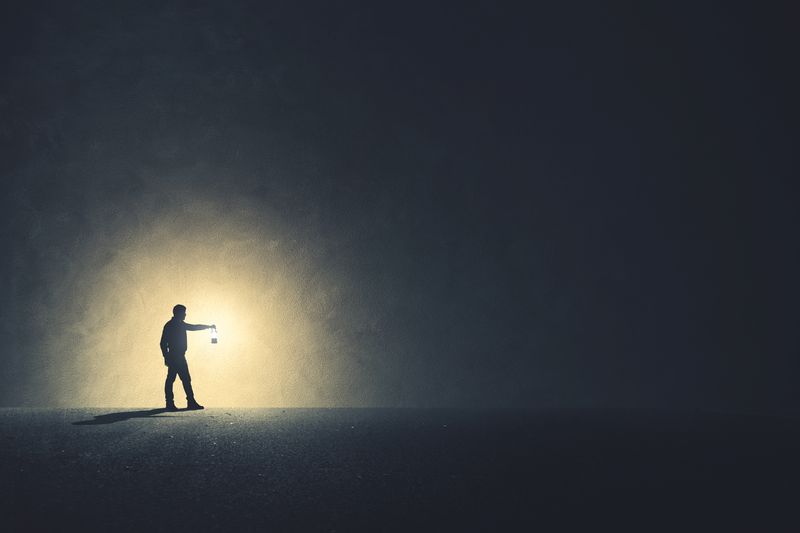 Man walking in the dark with lamp illuminating his path