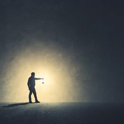 Man walking in the dark with lamp illuminating his path