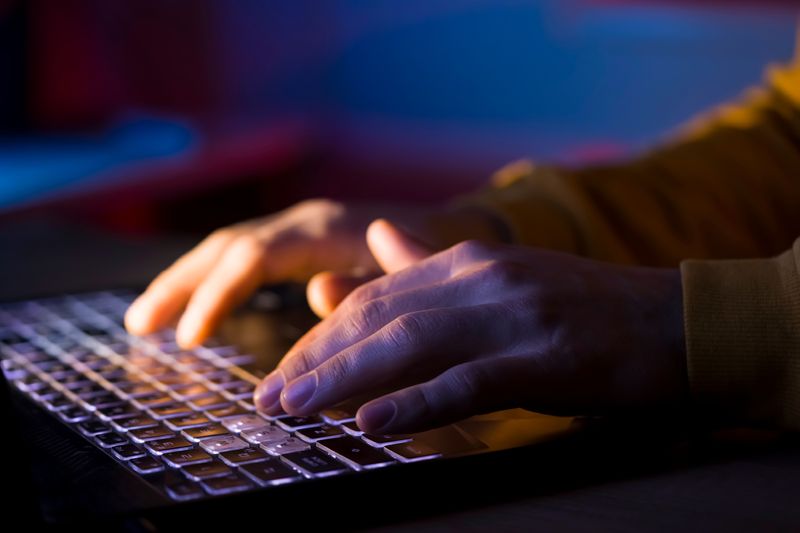 Close-up of hands typing on a laptop keyboard.