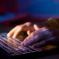 Close-up of hands typing on a laptop keyboard.