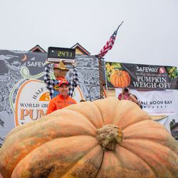 Man standing beside his massive award-winning pumpkin