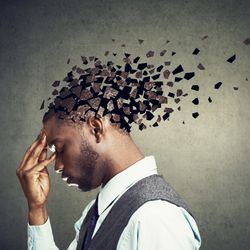 young Black man wearing a suit facing towards the left holding head in hand, with top of head crumbling into pieces to signify memory loss