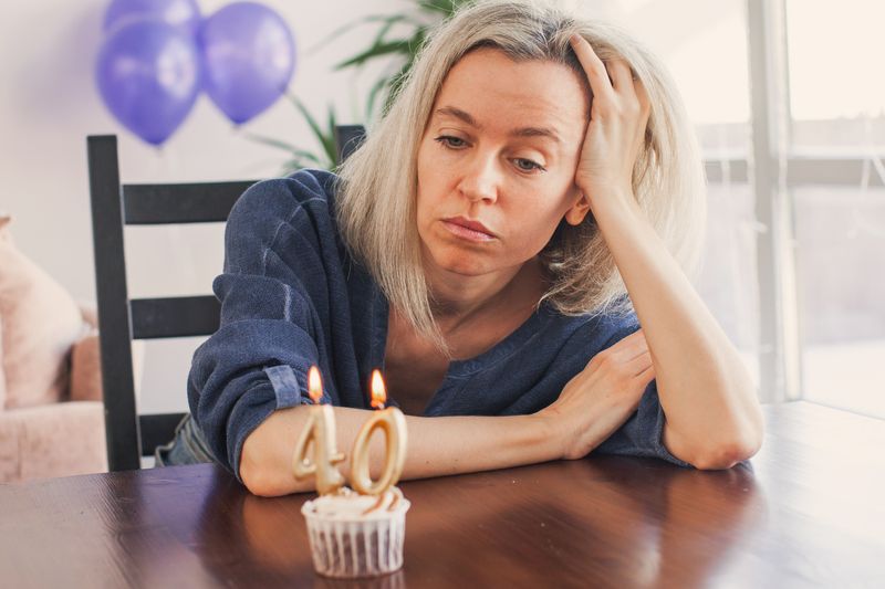 Sad woman staring at a cupcake with "40" candles