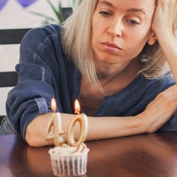 Sad woman staring at a cupcake with "40" candles