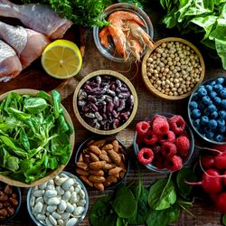 Fruit, vegetables, meat, fish, nuts, beans, and grains arranged on a wooden floor