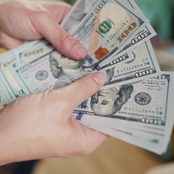 close up of hands counting 100 dollar bills