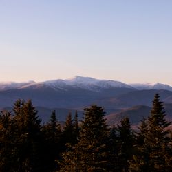 Sunset, distant mountains in the background, forest in the foreground